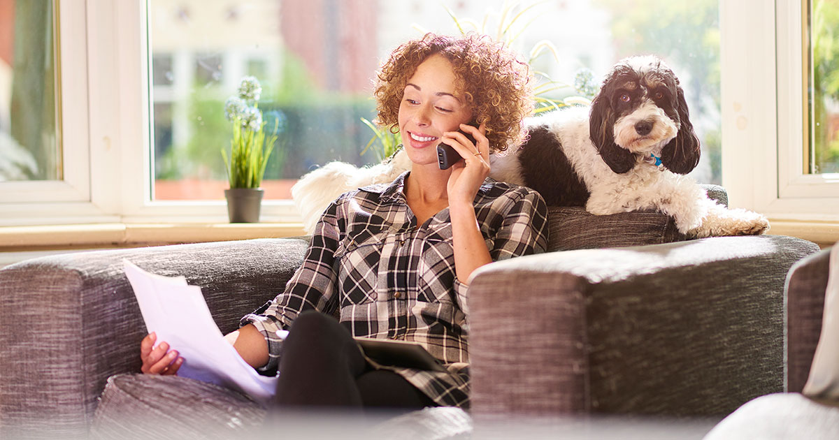woman on cordless phone with dog on sofa
