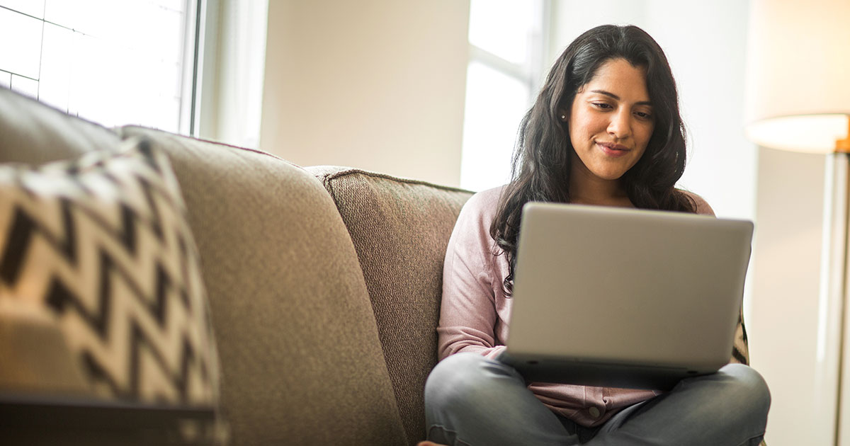 woman sitting on a sofa using a laptop