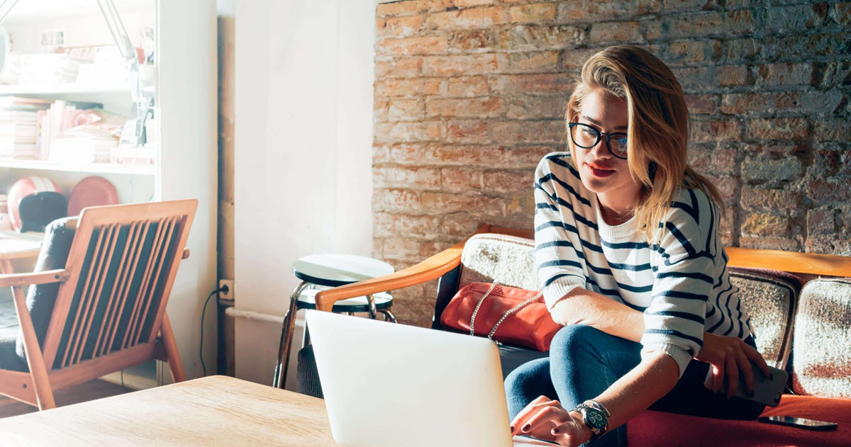 Una joven blanca usando una computadora portátil en una mesa de café