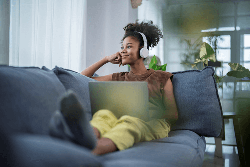 Woman relaxing on couch using the internet and listening to headphones